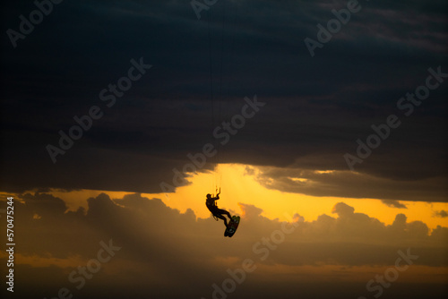 silhouette of person in the sunset sky doing kitesurfing