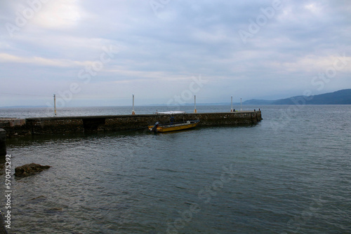 A small yellow motorboat stands in the bay near the pier.