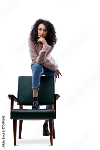 Young woman dominates chair, victoriously, in pink and jeans