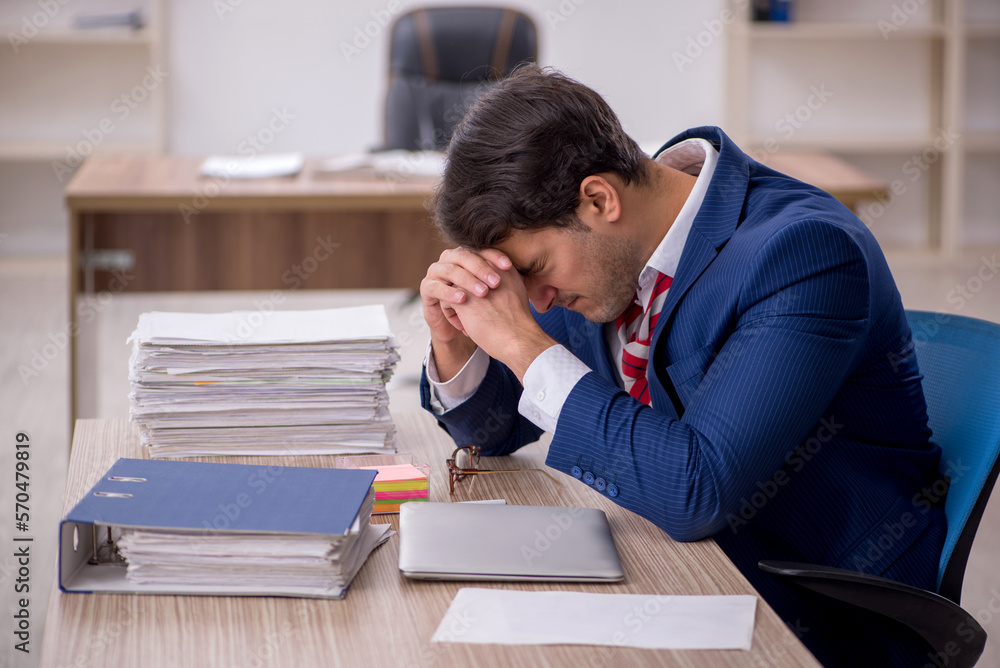 Young male employee and too much work in the office Young male employee and too much work in the office