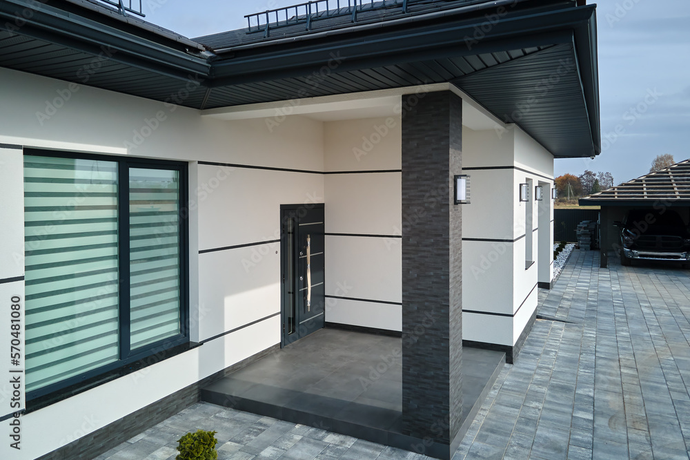 Fototapeta premium Exterior of modern contemporary comfortable house with front porch, stylish door, paved yard and shuttered windows