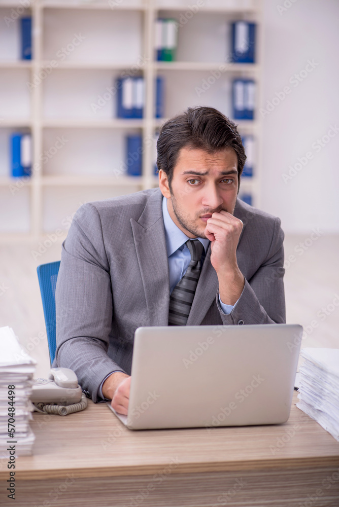 Young male employee and too much work at workplace Young male employee and too much work at workplace
