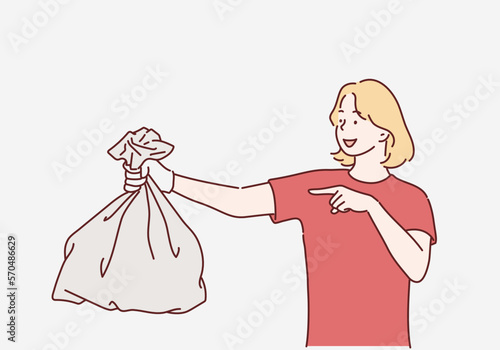 Young woman holding a garbage bag and pointing isolated on gray background. Hand drawn style vector design illustrations.