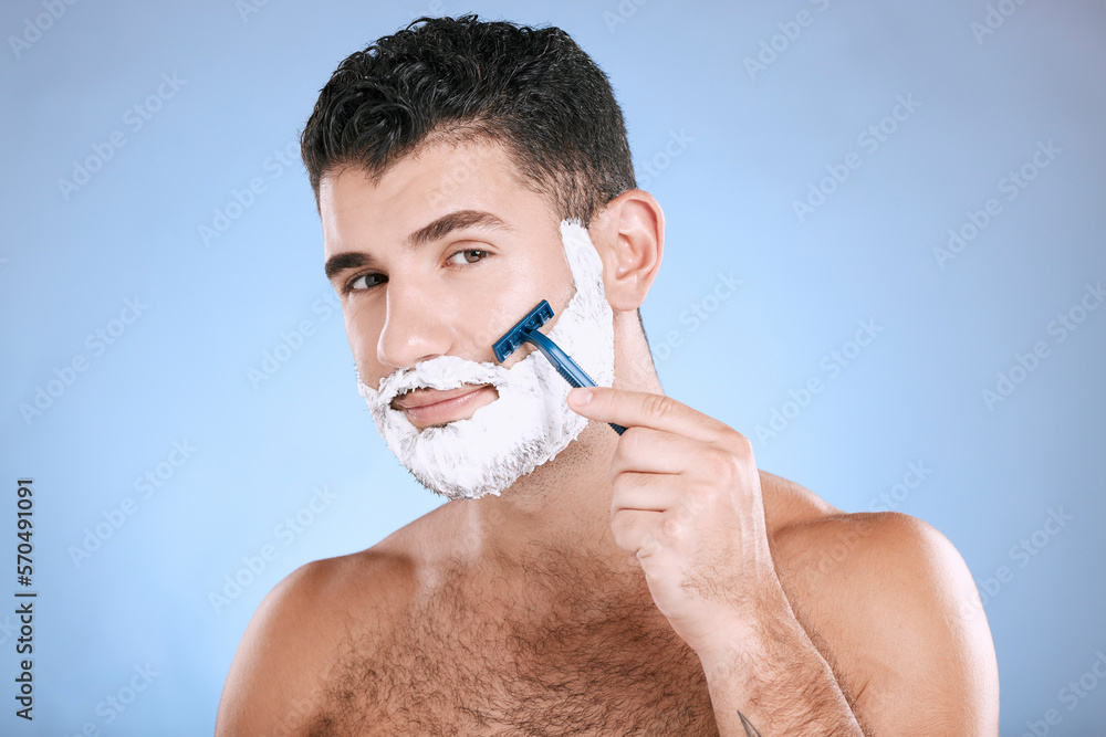 Shaving, grooming and portrait of a man with cream for beard isolated on a blue background. Skincare, beauty and model with razor to shave hair on face with foam for a clean facial look on a backdrop