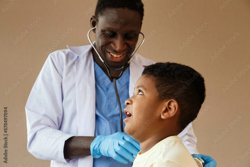 african american pediatrician doctor using stethoscope to examining boy from sickness in office at the hospital. medical and healthy. african american pediatrician doctor using stethoscope to examining boy from sickness in office at the hospital. medical and healthy.