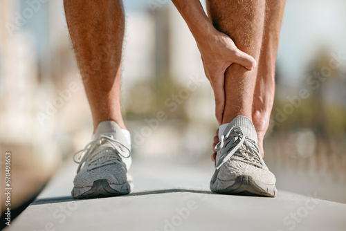 Ankle pain of runner or man hands for fitness healthcare risk, muscle accident or training problem in city. Running, cardio and workout foot injury of athlete person stop in street for legs massage