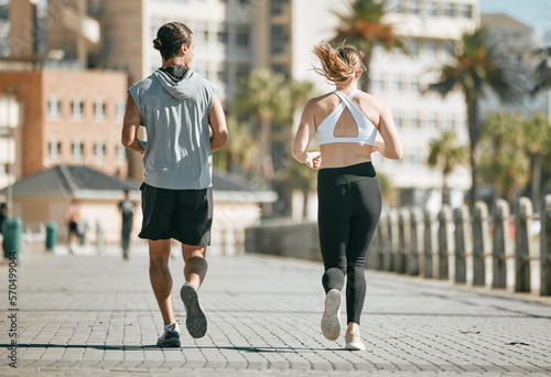 Fitness  teamwork or coaching with a runner couple on the promenade for cardio or endurance from the back. Exercise  wellness or workout with a man and woman athlete running outdoor in the city