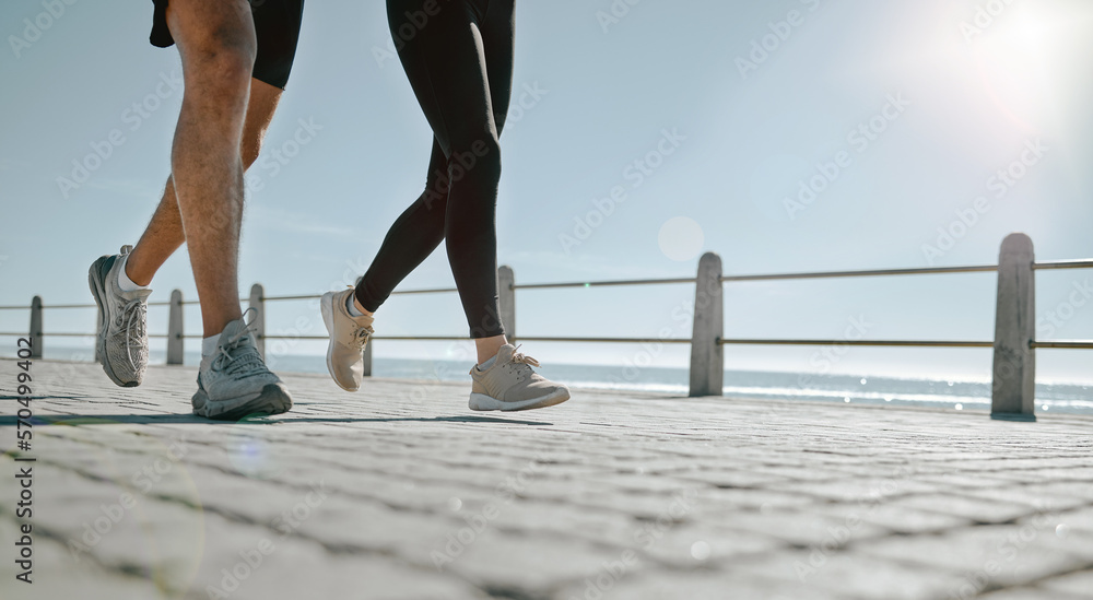 People, legs and running at the beach for exercise, cardio workout or training together outdoors. Leg of friends taking run, walk or jog on warm sunny day by the ocean coast for healthy wellness - obrazy, fototapety, plakaty 