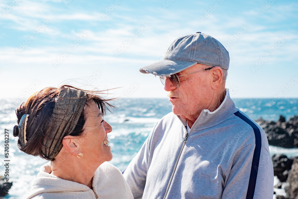 Caucasian senior couple in vacation at sea enjoying sunny day. Elderly people in vacation or retirement at sea expressing love and freedom