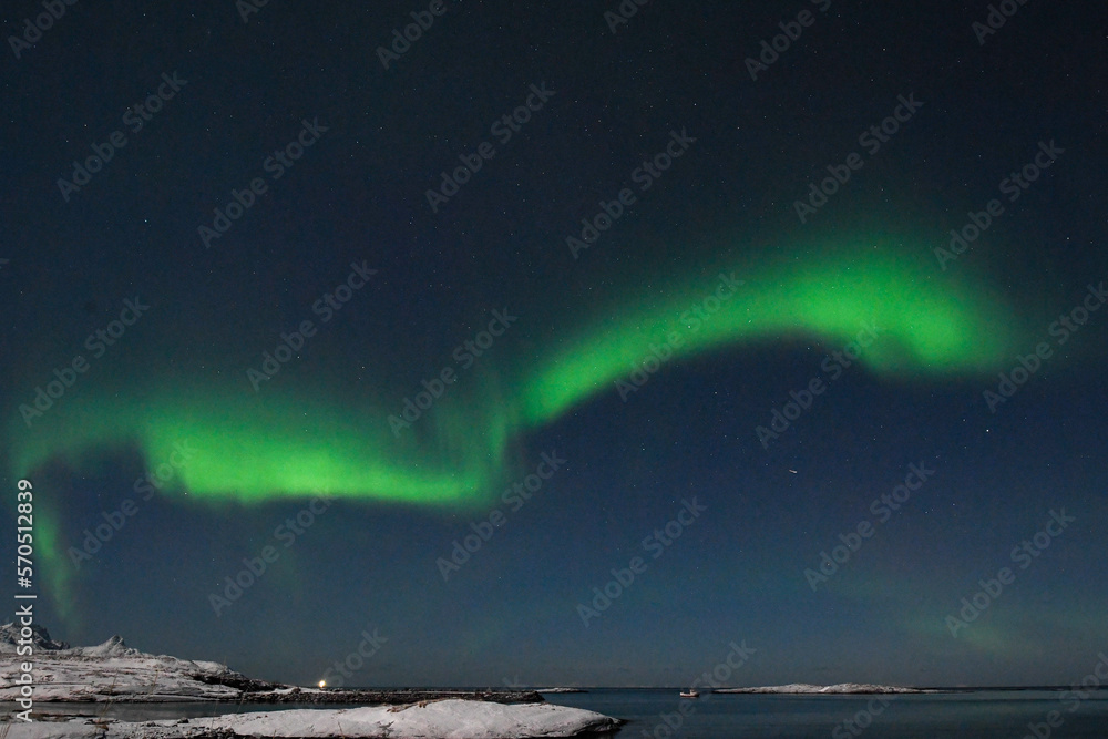 Bright Green Colours of the Northern Light, Aurora Borealis illuminate the Night Sky over the beach at Mjelle, in Arctic Norway.