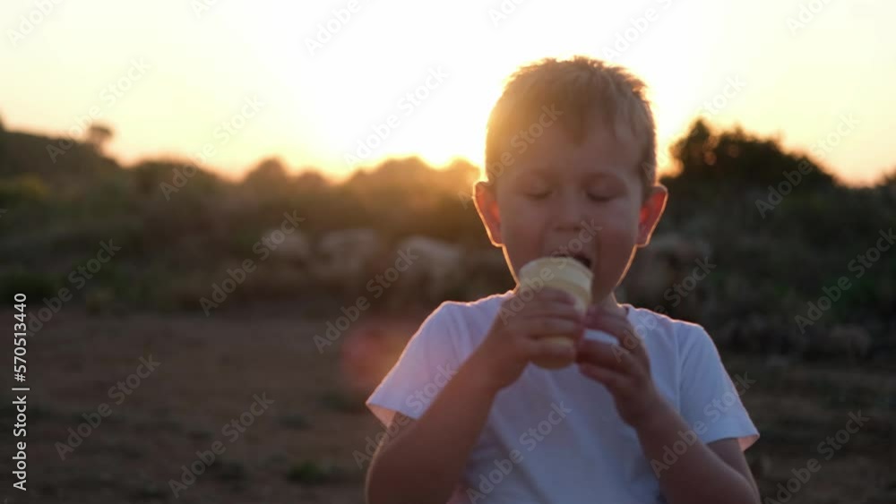 Little boy eats ice cream. A child licks a sundae against the backdrop of sunset