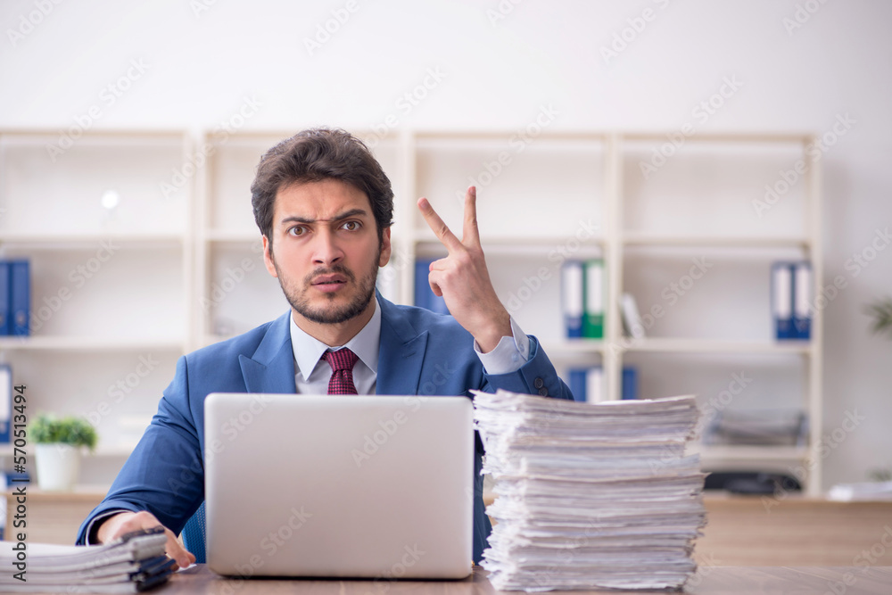 Young male employee and too much work in the office Young male employee and too much work in the office