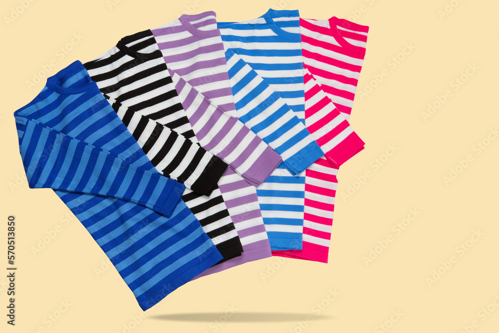 Four sweaters in stripes of different colors, as if walking, hugging each other, concept, on a yellow background Four sweaters in stripes of different colors, as if walking, hugging each other, concept, on a yellow background