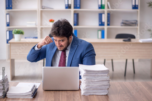 Young male employee and too much work in the office