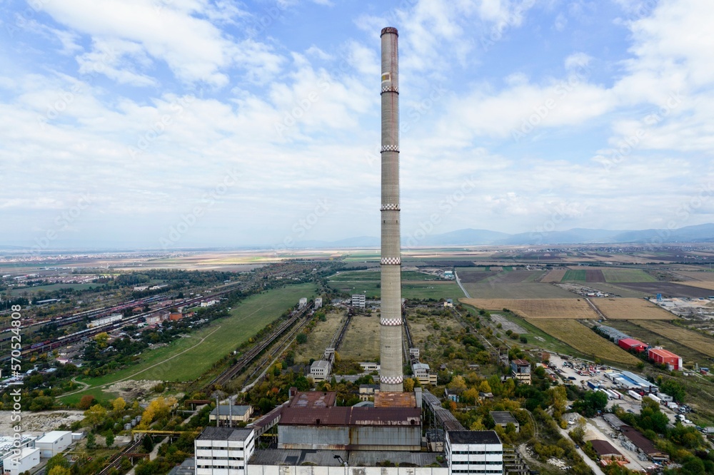 An aerial shot from drone capturing the massive towering smokestack of a retired coal-fired thermal power plant. It was used to exhaust combustion gases into the air