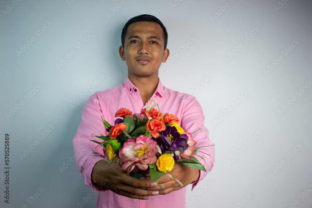 Portrait of Asian young man holding flower wearing pink shirt isolated on white background. Portrait of Asian young man holding flower wearing pink shirt isolated on white background.
