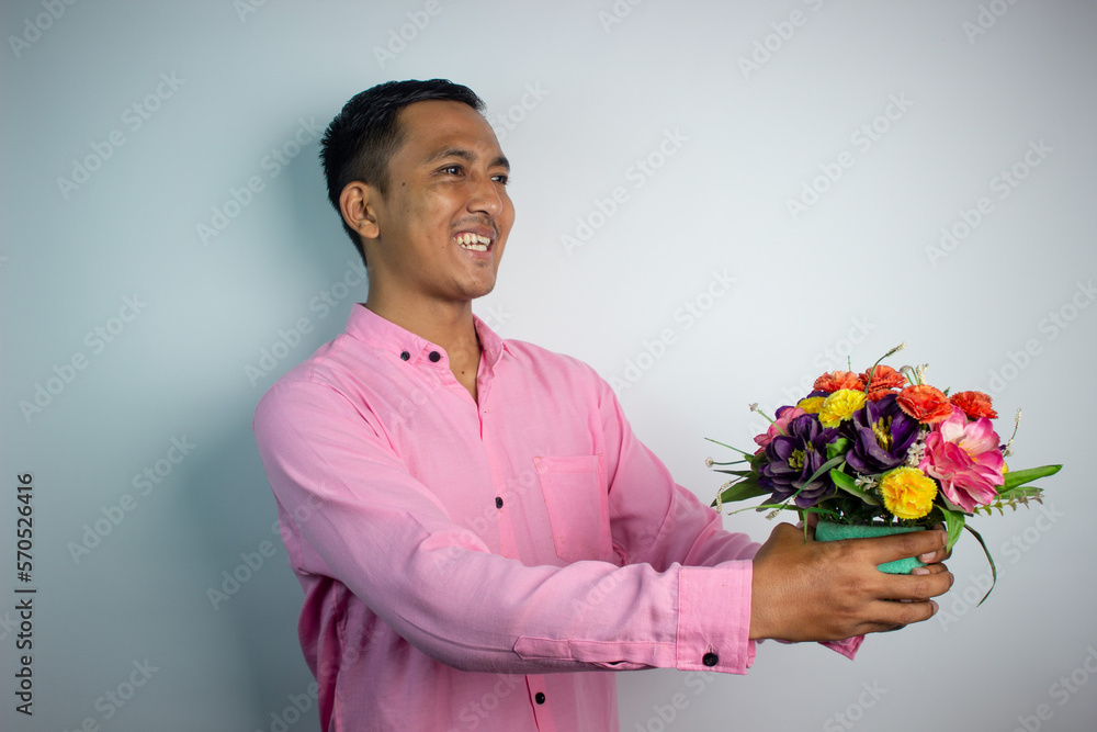 Portrait of Asian young man holding flower wearing pink shirt isolated on white background. Portrait of Asian young man holding flower wearing pink shirt isolated on white background.