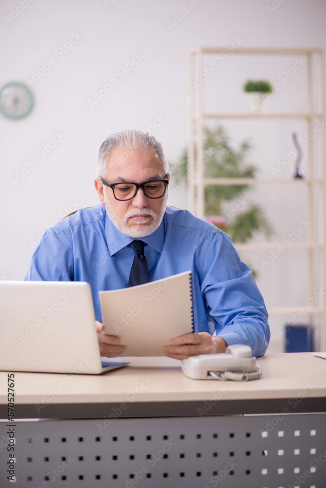 Old male employee working in the office Old male employee working in the office