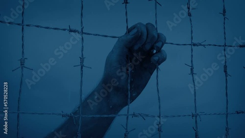 Snow Falls On Hand Holding Fence In The Dark photo