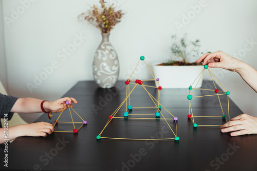 Mother and son  making geometric shapes from sticks and play dough. photo