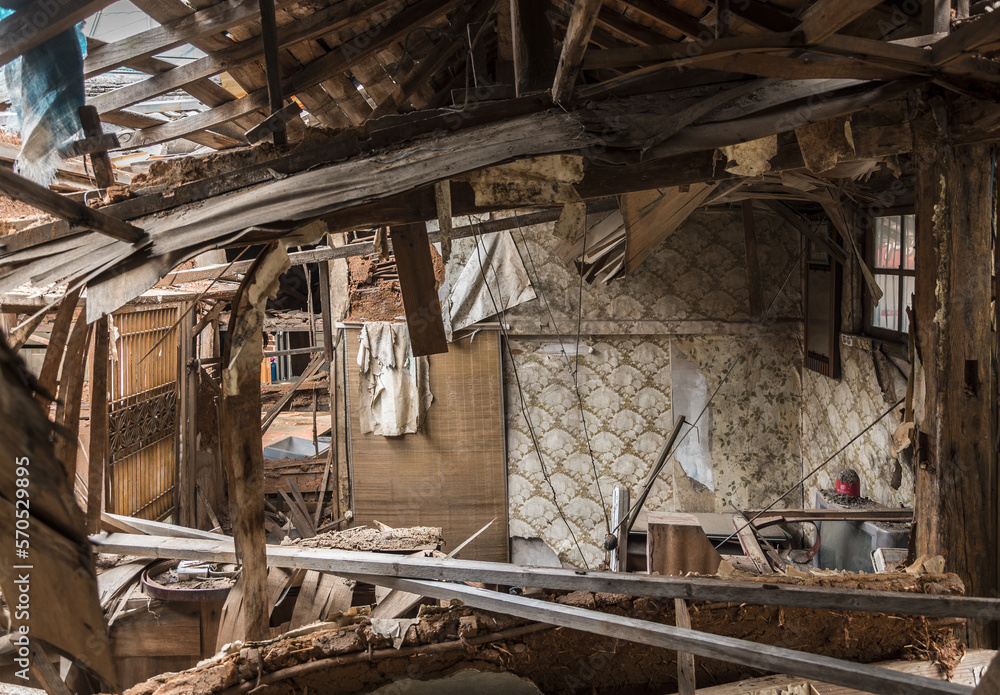 Urbex, destroyed room of an abandoned traditional South-Korean house, the walls, door and windows are broken, the roof collapsed, there are remains on the floor, the room is messy, dirty and dusty