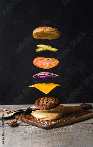 Burger with separated floating ingredients on black background.