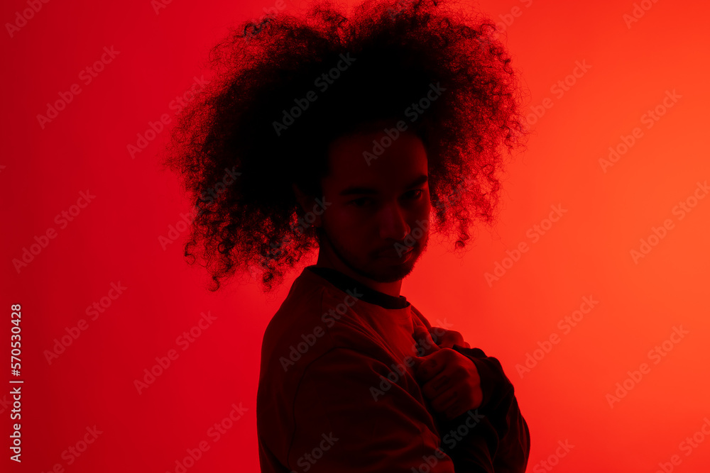 Silhouette in red light with arms crossed. Young man with afro hair on white background Silhouette in red light with arms crossed. Young man with afro hair on white background