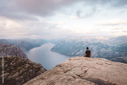 Man sitting in rock at edge of cliff at Preikestolen, Norway
