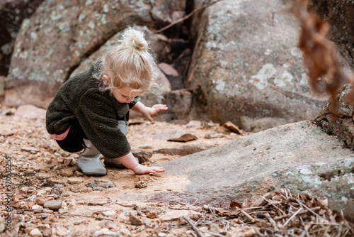 Child playing in sand along rocky river photo