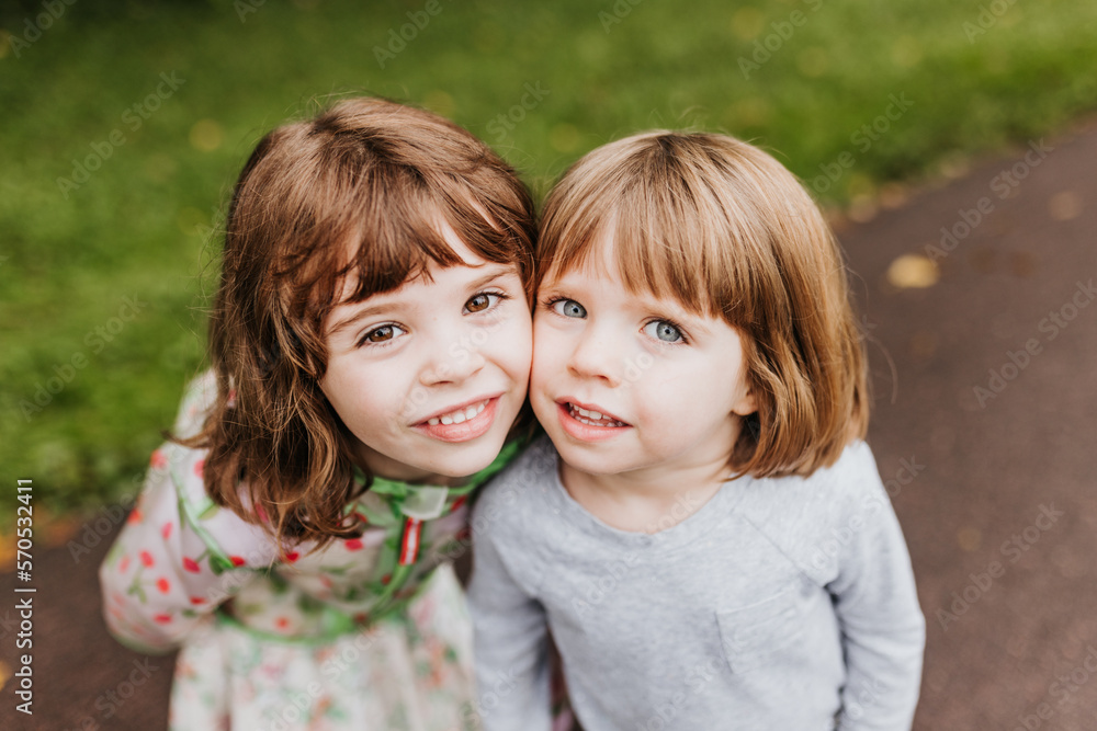 Close up of sisters squishing cheeks while standing outside Close up of sisters squishing cheeks while standing outside