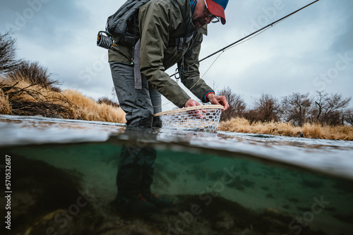 Underwater photo of fly fisherman unhooking fish in net photo