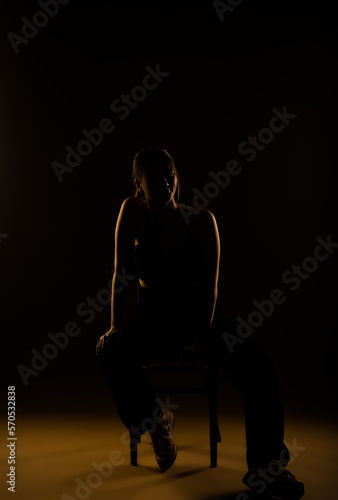 A full length photo of a girl posing in black outfit while sitting on a chair