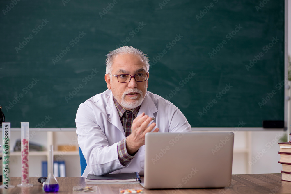 Old male teacher chemist sitting in the classroom Old male teacher chemist sitting in the classroom