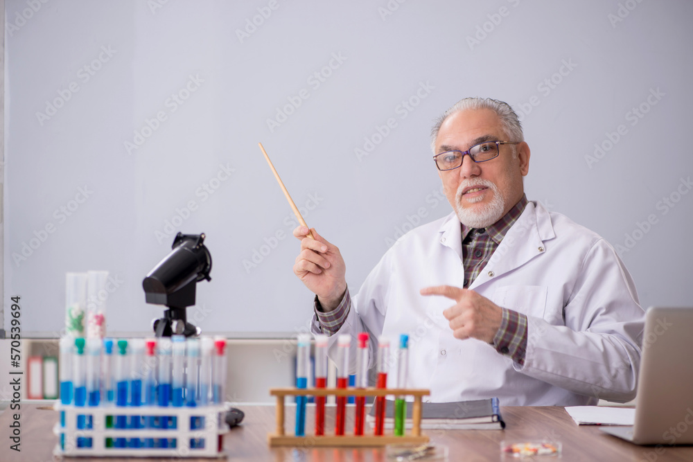 Old male teacher chemist sitting in the classroom Old male teacher chemist sitting in the classroom