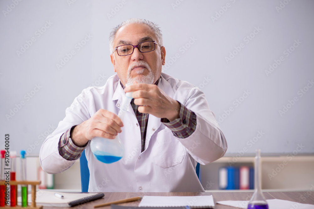 Old male teacher chemist sitting in the classroom Old male teacher chemist sitting in the classroom