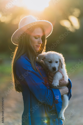 Chica joven con cachorro posando al atardecer en un bosque