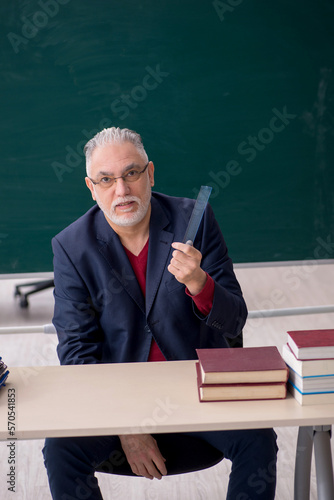 Old male teacher sitting in the classroom