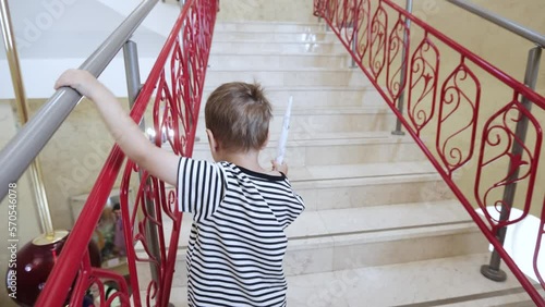 A boy in a striped T-shirt climbs the Beautiful twisted staircase with hanging balls photo