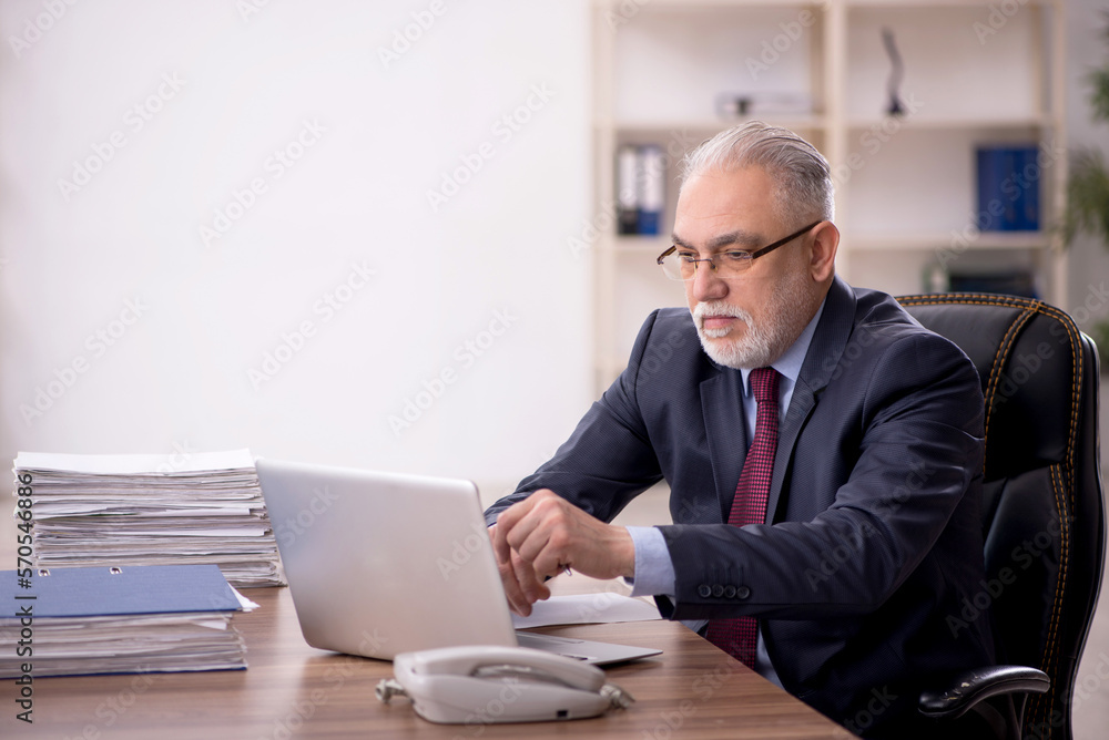 Old male boss working at workplace Old male boss working at workplace