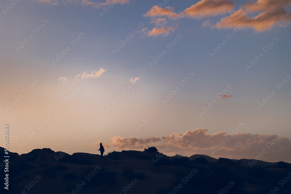 Silhouette of a boy walking on the rocks at sunset