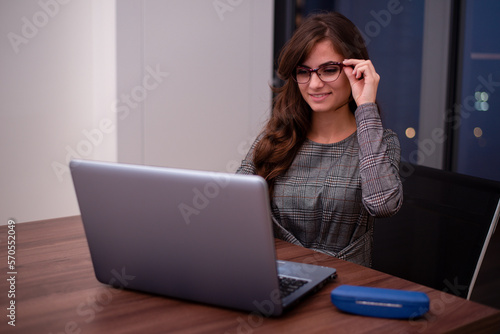 Businesswoman holding her glasses while working on her laptop