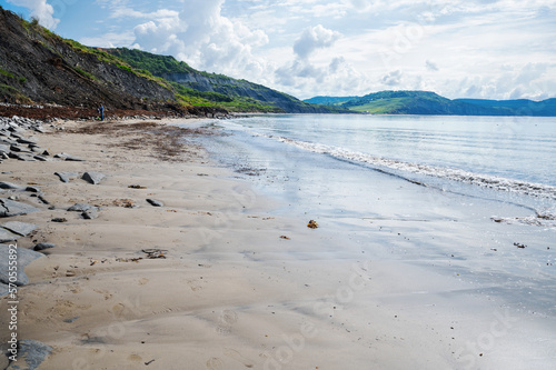 Famous Lyme Regis beach, world heritage site in Dorset, South West England. View of stones and liffs and blue sea. The beach is full of fossils. Selective focus photo