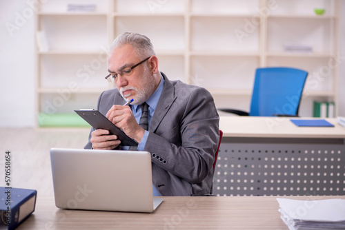 Old male employee working in the office