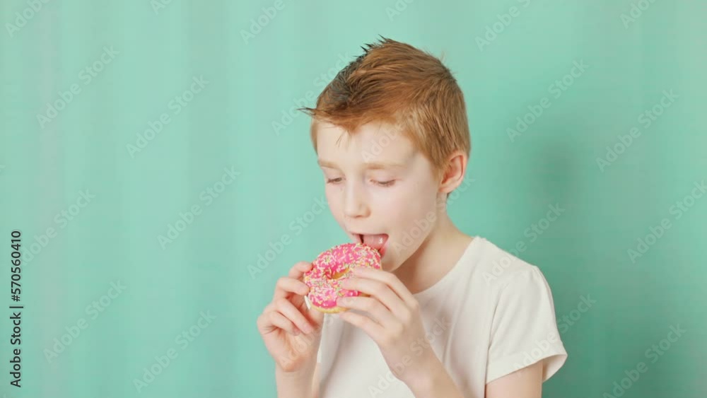 Boy eating donuts on the green background in a National doughnut day. Slow motion video. Boy eating donuts on the green background in a National doughnut day. Slow motion video.