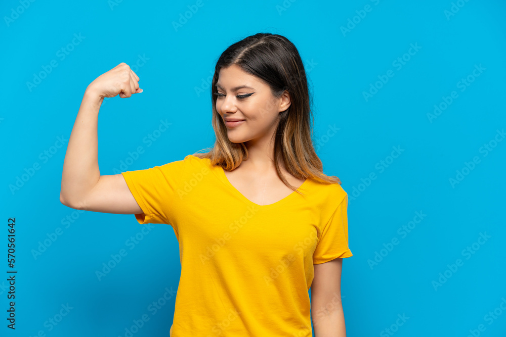 Young Russian girl isolated on blue background doing strong gesture Young Russian girl isolated on blue background doing strong gesture