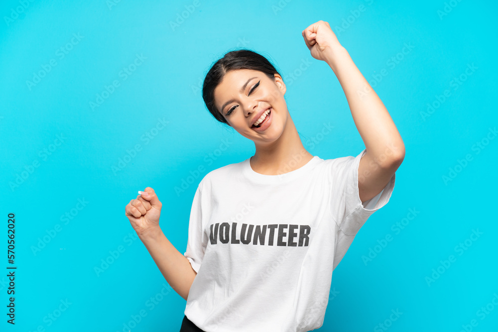 Young Russian volunteer girl isolated on blue background celebrating a victory Young Russian volunteer girl isolated on blue background celebrating a victory