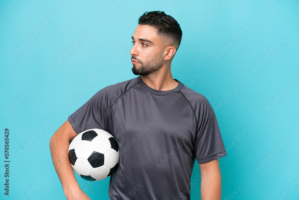 Young Arab handsome man isolated on blue background with soccer ball