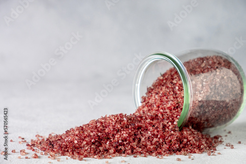 Red wine flavored salt spills out of a glass jar.  Gourmet condiment to aromatize and season food Dessert, Seafood, Meats, Pasta, Sauce, Finishing Salt