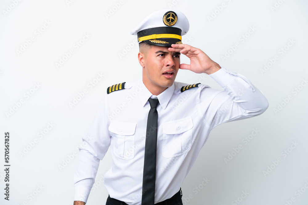 Airplane pilot caucasian man isolated on white background looking far away with hand to look something Airplane pilot caucasian man isolated on white background looking far away with hand to look something