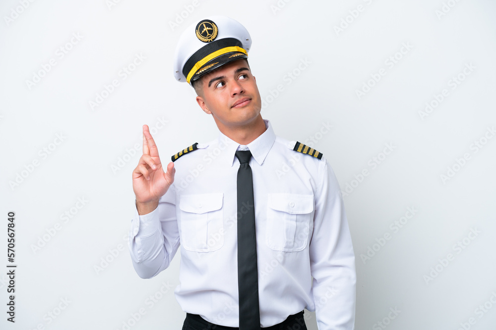 Airplane pilot caucasian man isolated on white background with fingers crossing and wishing the best Airplane pilot caucasian man isolated on white background with fingers crossing and wishing the best